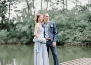 Hochzeitspaar steht lächelnd auf Steg beim Pröllweiher in Meitingen