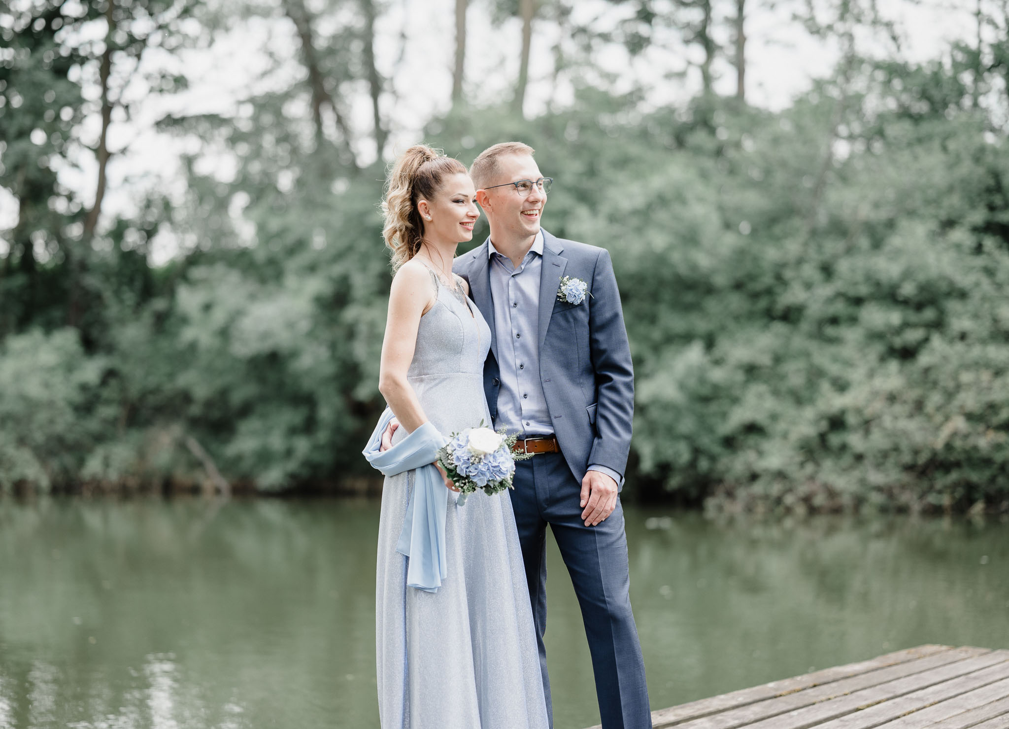 Hochzeitspaar steht lächelnd auf Steg beim Pröllweiher in Meitingen